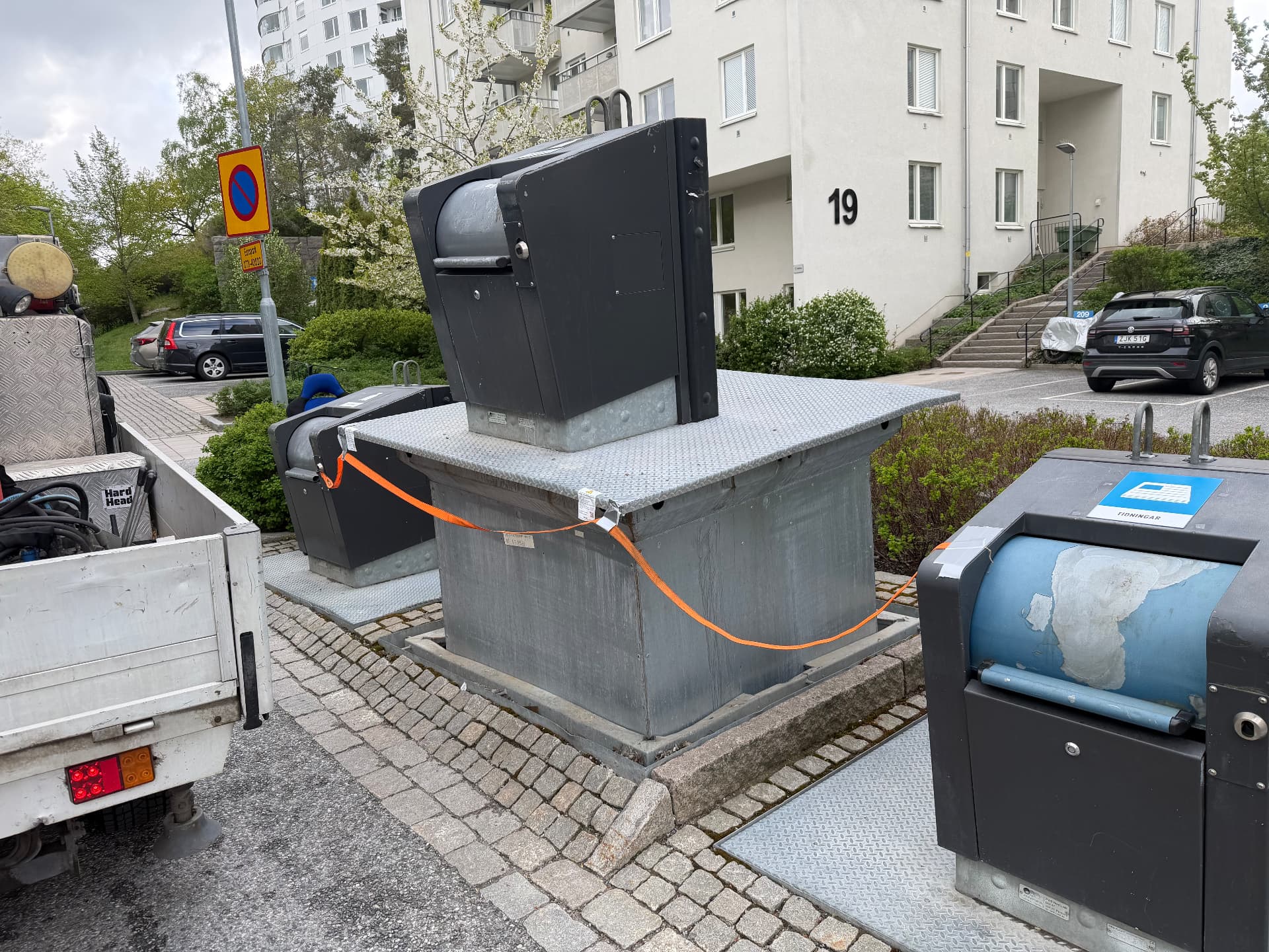 Bottenöppande behållare lyft av kranbil med öppet schakt intill