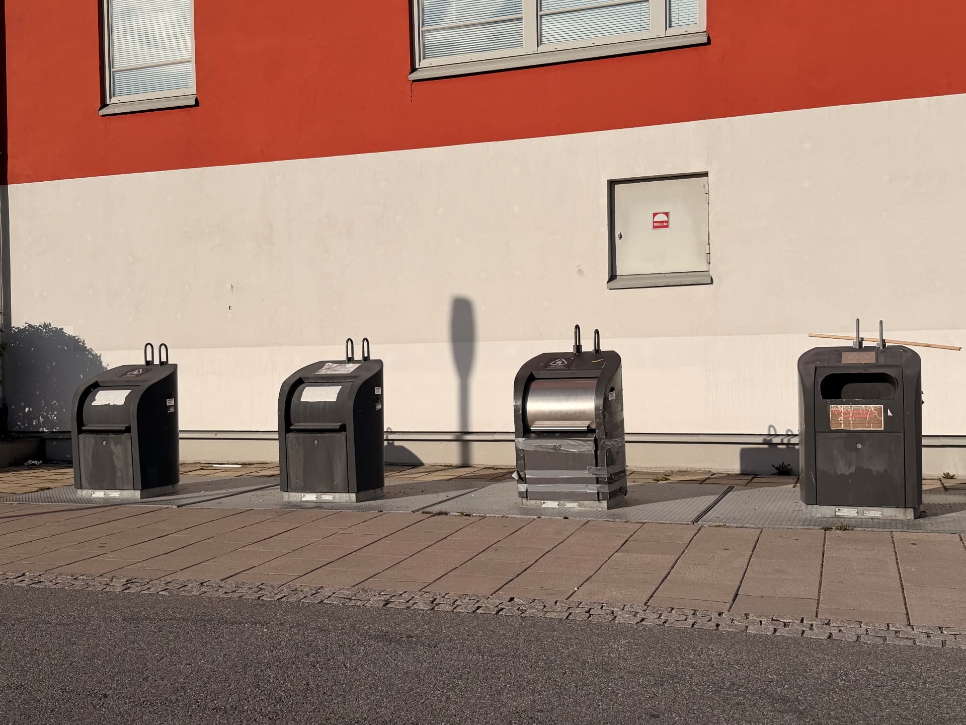 Rad med bottenöppande avfallsbehållare på tömningsplatser utanför ett bostadshus